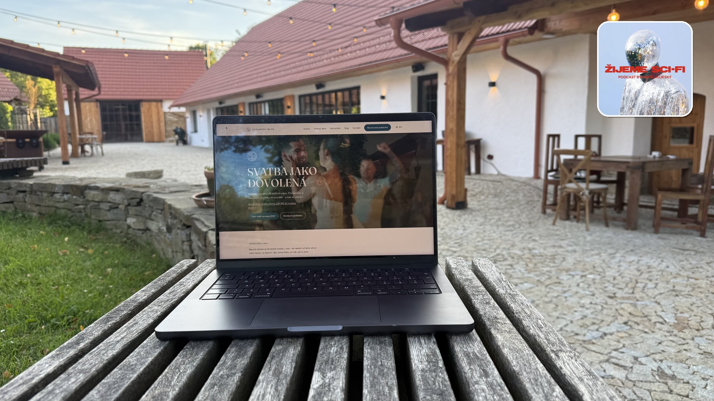Notebook na lavici na nádvoří Kománkova mlýna, na obrazovce stránka s cenou svatebního víkendu, v rohu obal podcastu Žijeme Sci-Fi